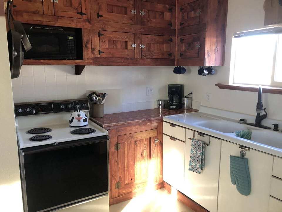 Small simple kitchen with stove, microwave.