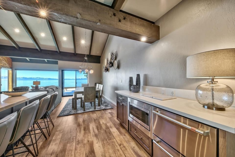 Your modern kitchen flows seamlessly into the dining area, where ocean views frame every meal through floor-to-ceiling windows.