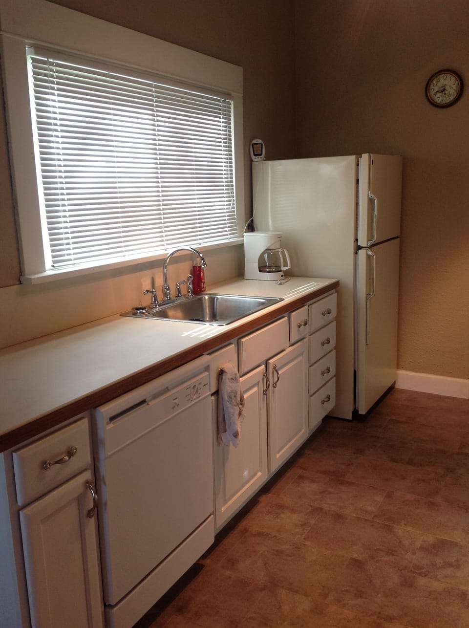Galley style kitchen with Dishwasher, frig, coffee pot, and utensils