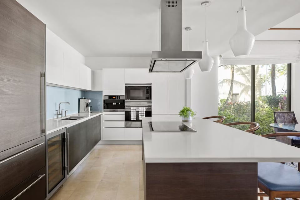 Center island w/ flush, induction stovetop below an in-line hooded exhaust fan

