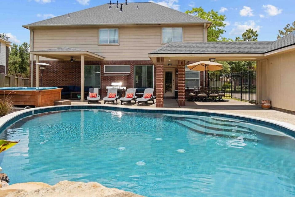 Spacious outdoor retreat featuring a private pool, freestanding hot tub, covered patio, loungers, and dining area—perfect for group hangouts.