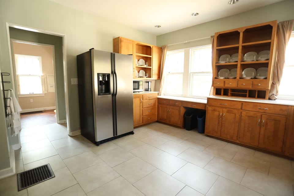 This big kitchen displays approximately half of the table settings on open shelving. The passageway to the left leads to the first floor half bath.  The passageway also provides access to another closet, stairs to the backyard/basement.
