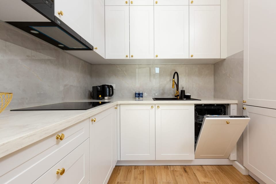 A compact kitchen with white cabinets, a black countertop, and all essential appliances.
