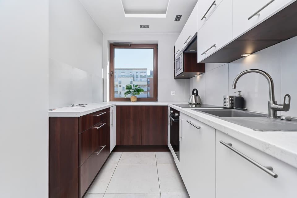 A modern kitchen with a combination of white and dark brown cabinets, stainless steel appliances, and a sleek countertop.