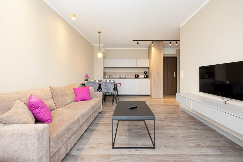 A spacious living area with a gray sofa and a dining table, connected seamlessly to the kitchenette.