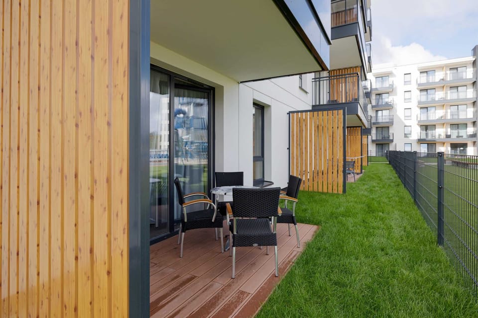 A small patio with chairs and a table, leading to a well-maintained grassy area.