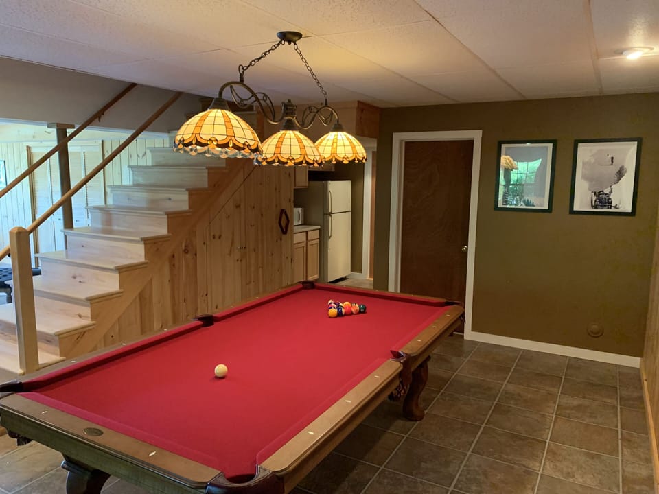 Basement game room is complete with pool table, dartboard & foosball table.