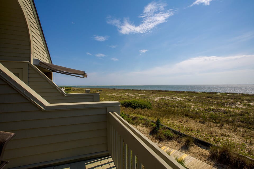 Bask under beautiful blue skies on your private porch & only steps to the beach