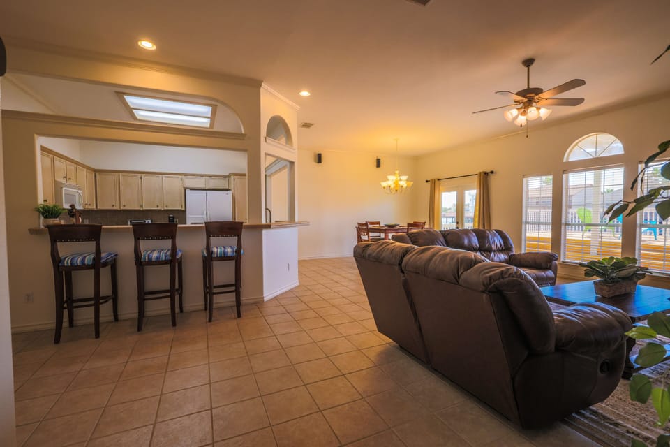 Hallway into family room and kitchen eating bar with bar stools 