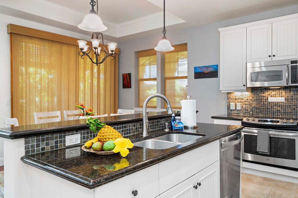 Well-equipped with white Hawaiian bungalow style cabinets and beautiful contrasting black granite countertops