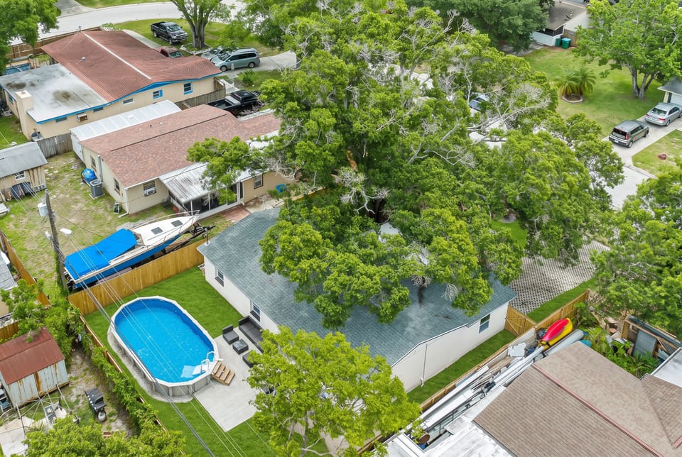 Pool, yard, and shade from the sky. From above you see the fenced backyard, the private pool, and a giant shade oak over the house. A rare mix of space, privacy, and greenery in a quiet Largo neighborhood.