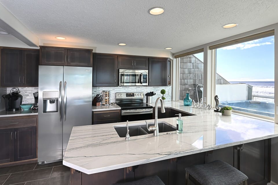 Sleek kitchen island w/ modern finishes and expansive ocean-facing windows.