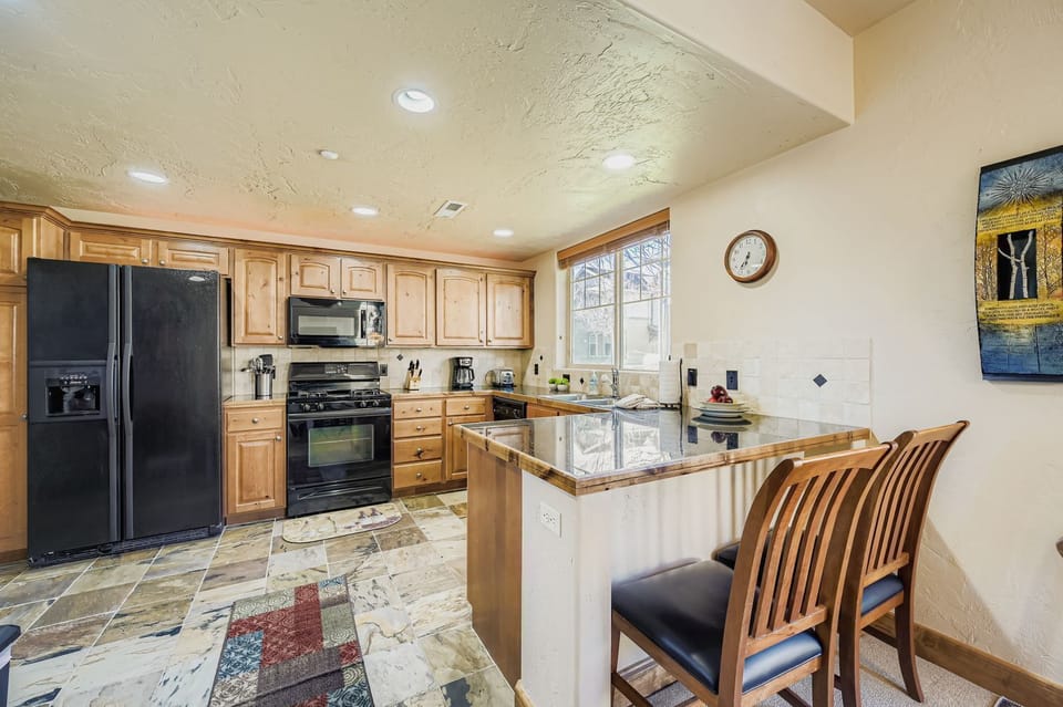 Cook your favorite meals in this fully equipped kitchen featuring granite countertops, modern appliances, and a convenient breakfast bar where you can enjoy your morning coffee.