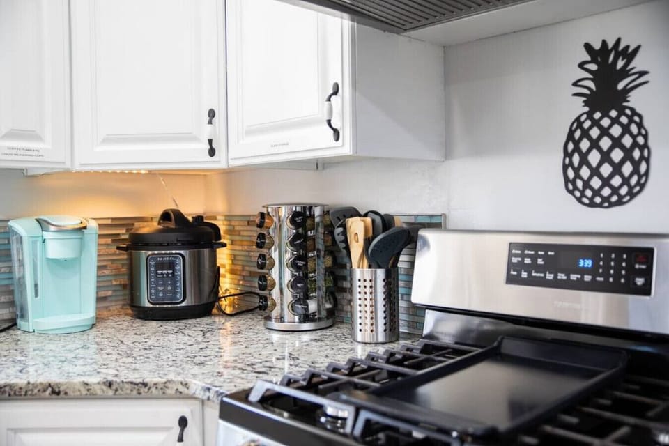 Modern kitchen with stainless steel stove, coffee maker, and stylish backsplash.