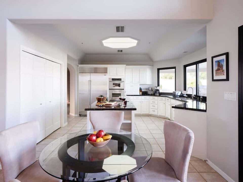 Fully equipped kitchen with stainless steel appliances, basic cooking essentials, dining table, and bright skylight!