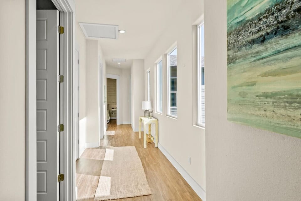 Spacious upstairs hallway with beach-inspired artwork and natural light.
