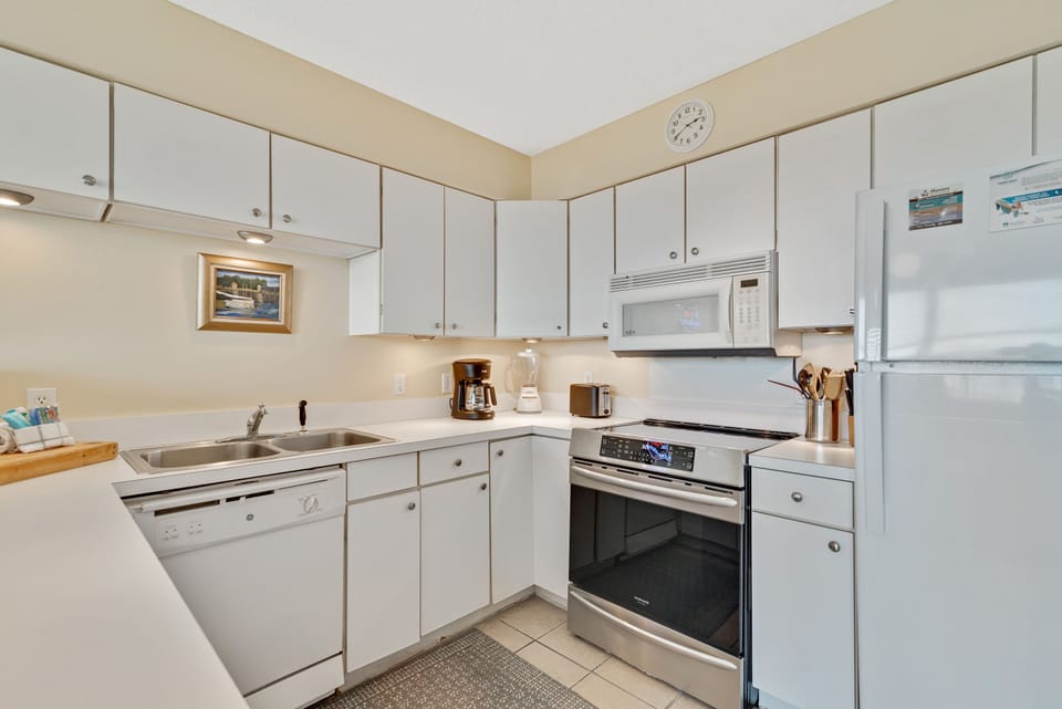 Prepare delicious meals in this bright and functional kitchen. Featuring sleek white cabinetry, updated appliances, and thoughtful amenities, it's designed for convenience, ensuring a comfortable stay.