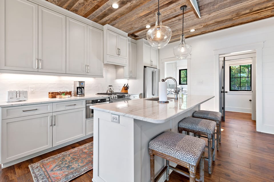 Luxury kitchen with bar seating, gas range, dishwasher, and drip-style coffeemaker.
