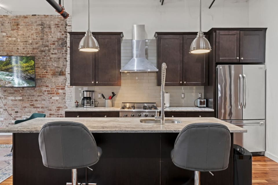 Stylish kitchen with bar seating, stainless appliances, and open shelving.