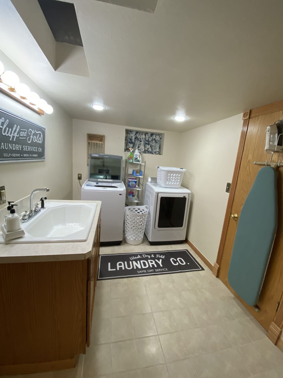 Laundry room with utility sink, new washer and dryer, ironing board and iron.