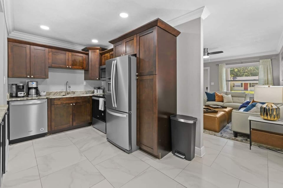 The kitchen features classic dark cabinets and stainless steel appliances, including a spacious refrigerator, oven, stovetop, and dishwasher. It’s fully stocked with all the essentials and offers both Keurig and drip coffee makers for your convenienc