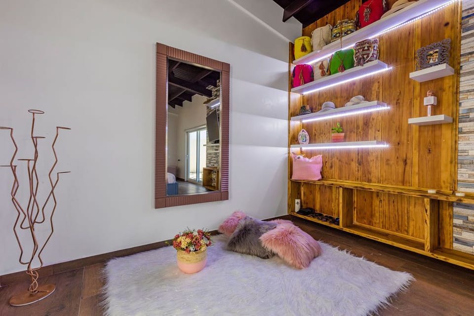 This bedroom features a feminine interior design. With an air-conditioning unit, a desk, TV, a balcony, a king bed, and a gorgeous bedframe.