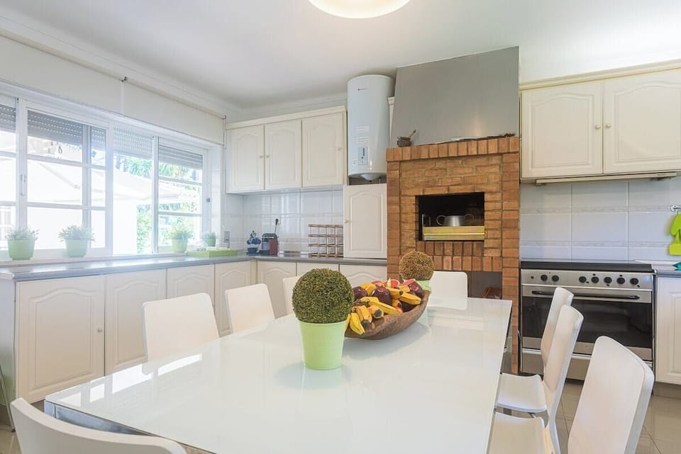 Modern open-plan kitchen with cream cabinets and brick fireplace — Villa Niki, luxury holiday villa in Grândola
