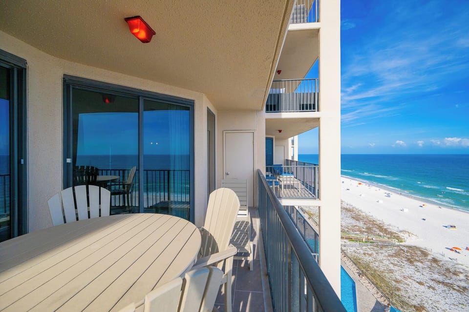 The balcony overlooks the coast with chairs and a table set for peaceful mornings or sunset views
