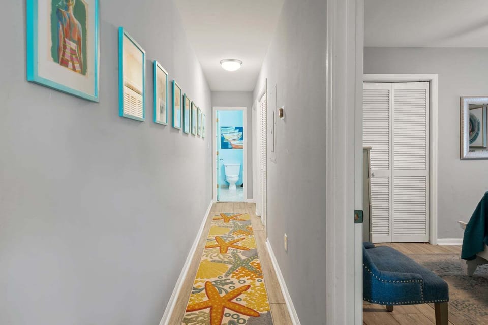 Hallway with a starfish runner and framed coastal art at Sea Lakes 103C, Cherry Grove