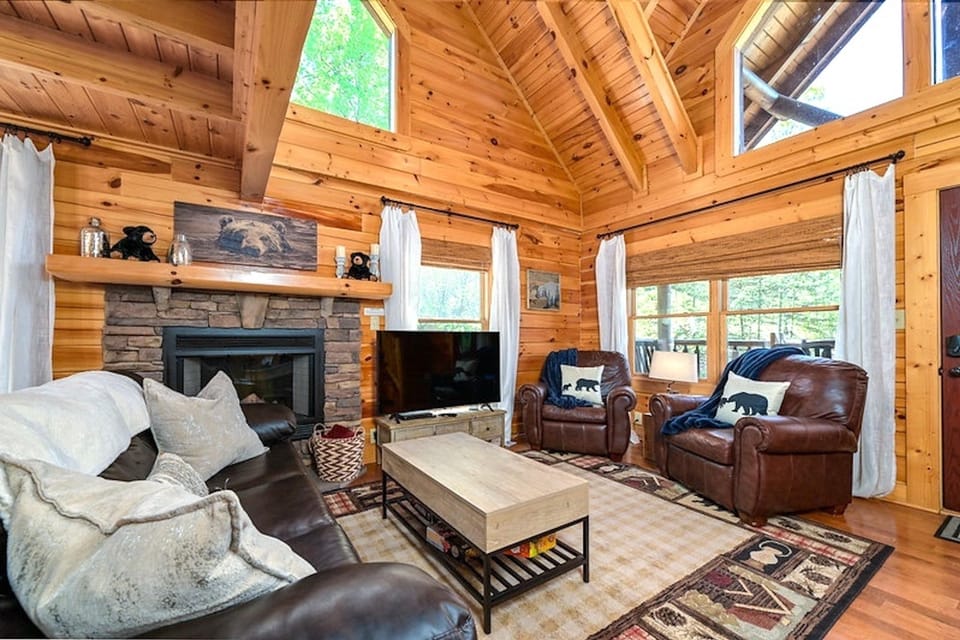 Cozy log cabin living room with vaulted ceilings and fireplace
