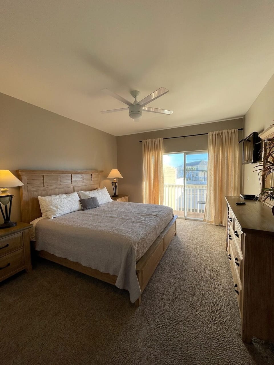 Unwind in your peaceful bedroom featuring a plush king bed, gentle ceiling fan, and private balcony overlooking scenic surroundings.