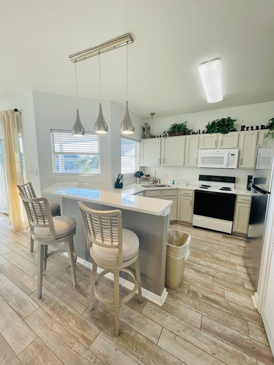 Your bright, fully equipped kitchen awaits with modern appliances, stylish pendant lighting, and a convenient breakfast bar perfect for morning coffee.