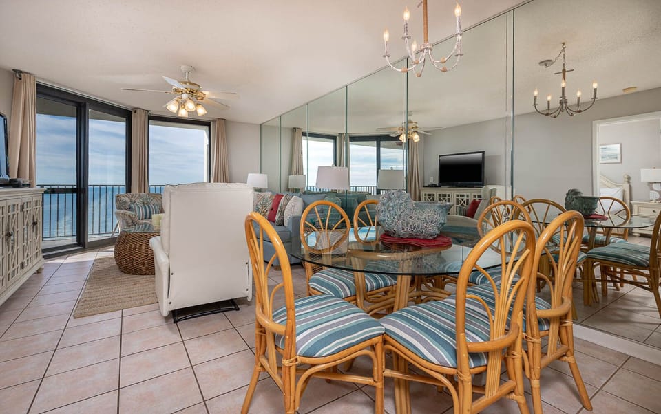 Bright dining area features a glass table with striped chairs, complemented by gulf views through expansive windows