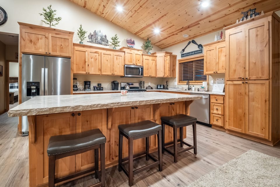 Kitchen features an island with barstool seats and modern appliances.