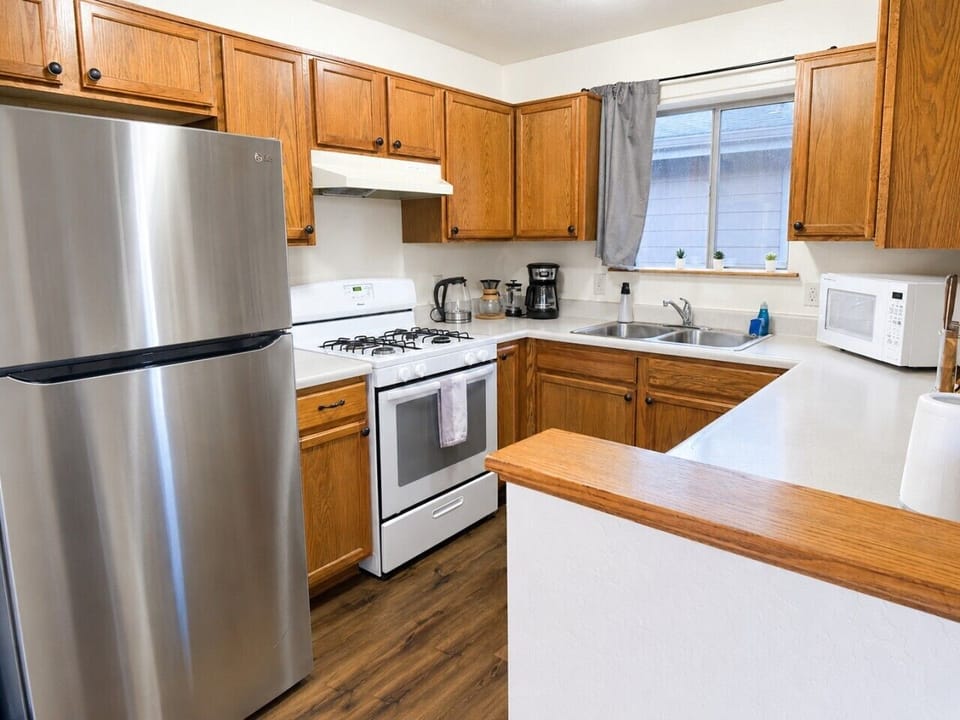 Bright, fully stocked kitchen with a full-size gas stove, microwave, drip coffee maker, French press, pour-over setup, kettle, cookware, dishes, and pantry basics for easy meals and mornings.