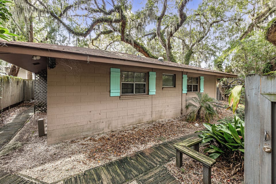 Concrete block exterior with teal shutters and trees