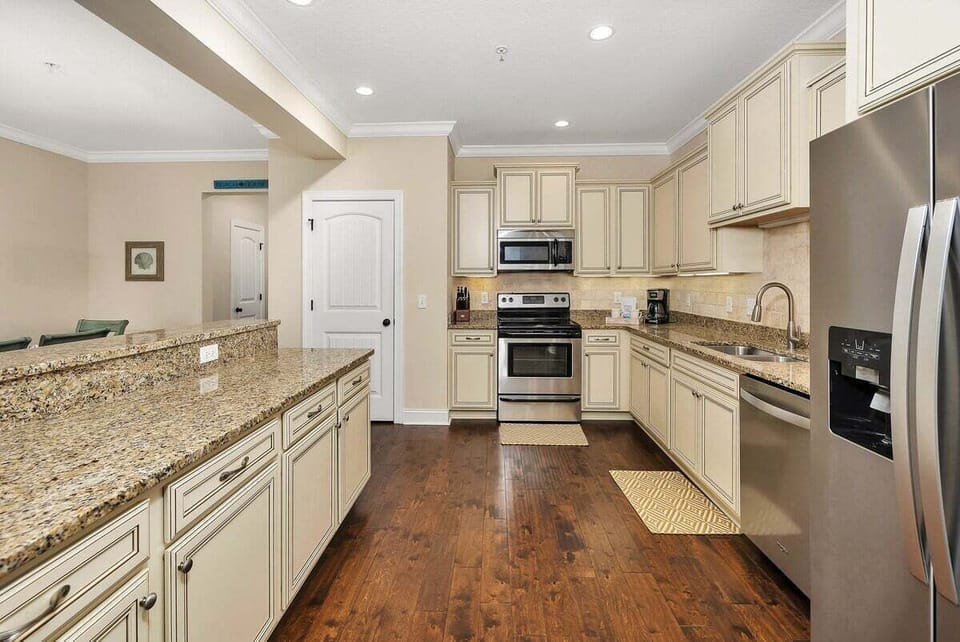 Kitchen with cream cabinets, granite island, and stainless appliances
