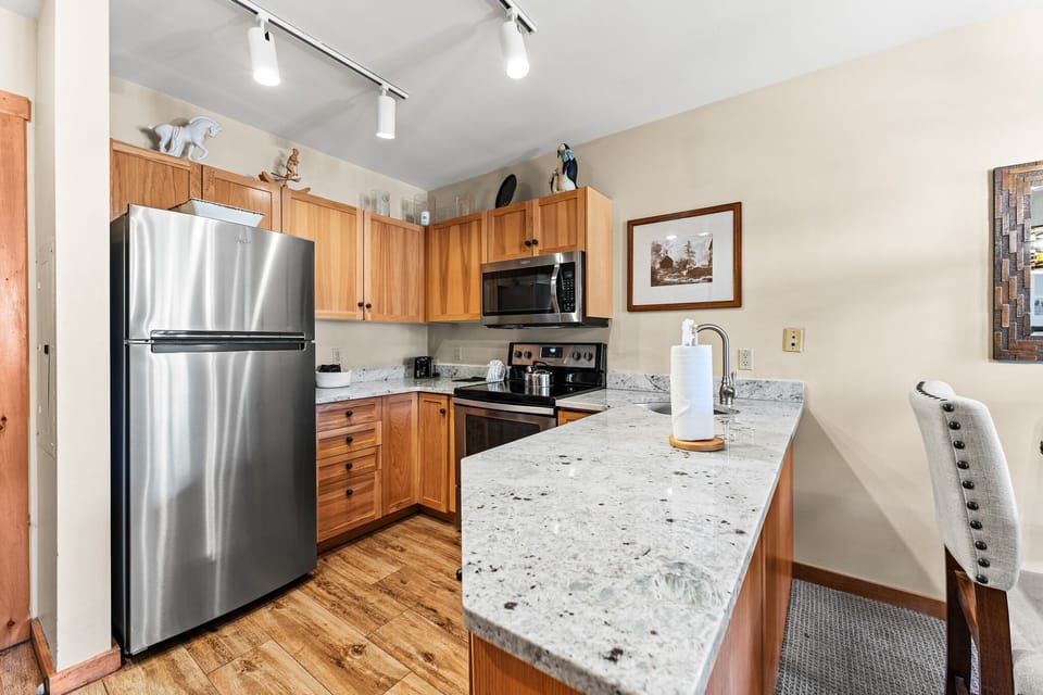 Your fully equipped kitchen features granite counters, stainless appliances, and warm wood cabinets for memorable home-cooked meals during your stay.