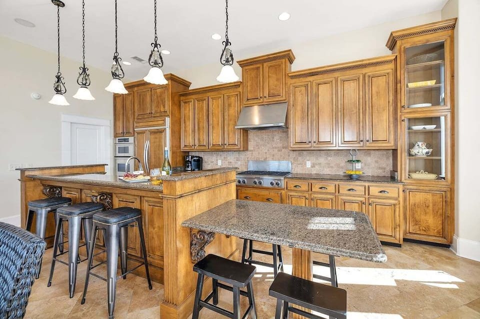 Wood kitchen with large island, bar stools, and pendant lights