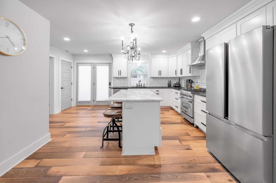Cook
dinner at the
waterfall-edge
island under
the three-globe chandelier —
plenty of
counter space
for a group
this size to
work together
instead of
taking turns.
