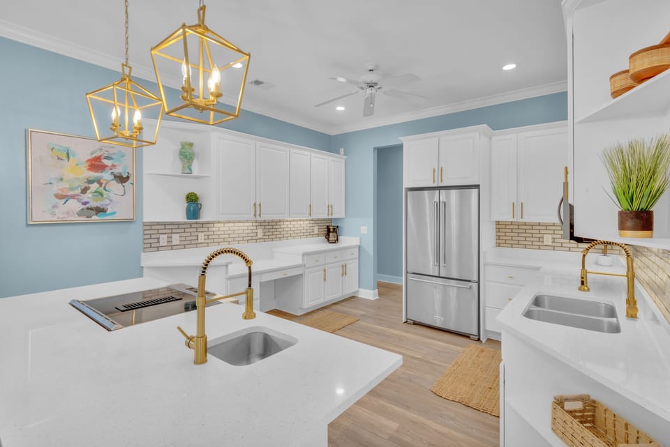 Spacious kitchen with stainless steel appliances, ample counter space, fully stocked essentials, and three barstools for additional seating.