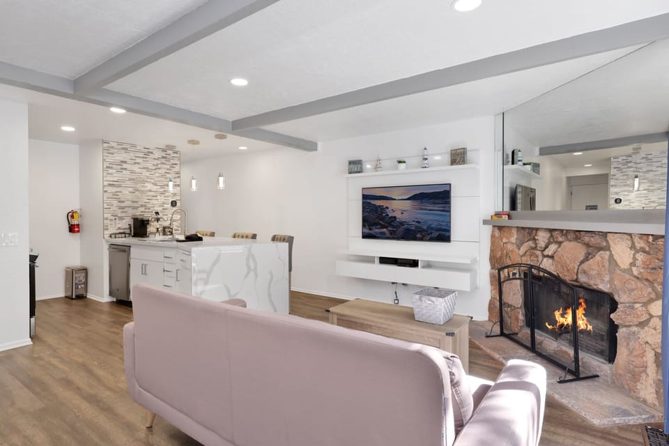 Cozy mountain living room with  a stone fireplace, comfy seating, and smart TV—perfect for relaxing evenings, movie nights, and warm cabin vibes after outdoor adventures.