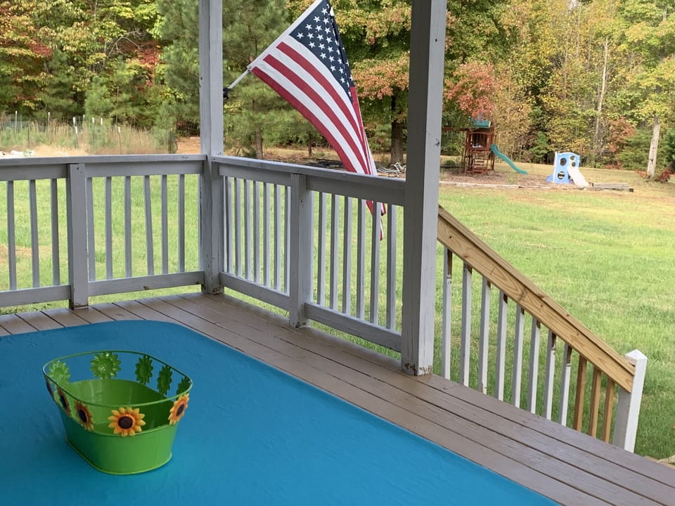 Covered front porch with view of play area and fire pit. Large front yard.