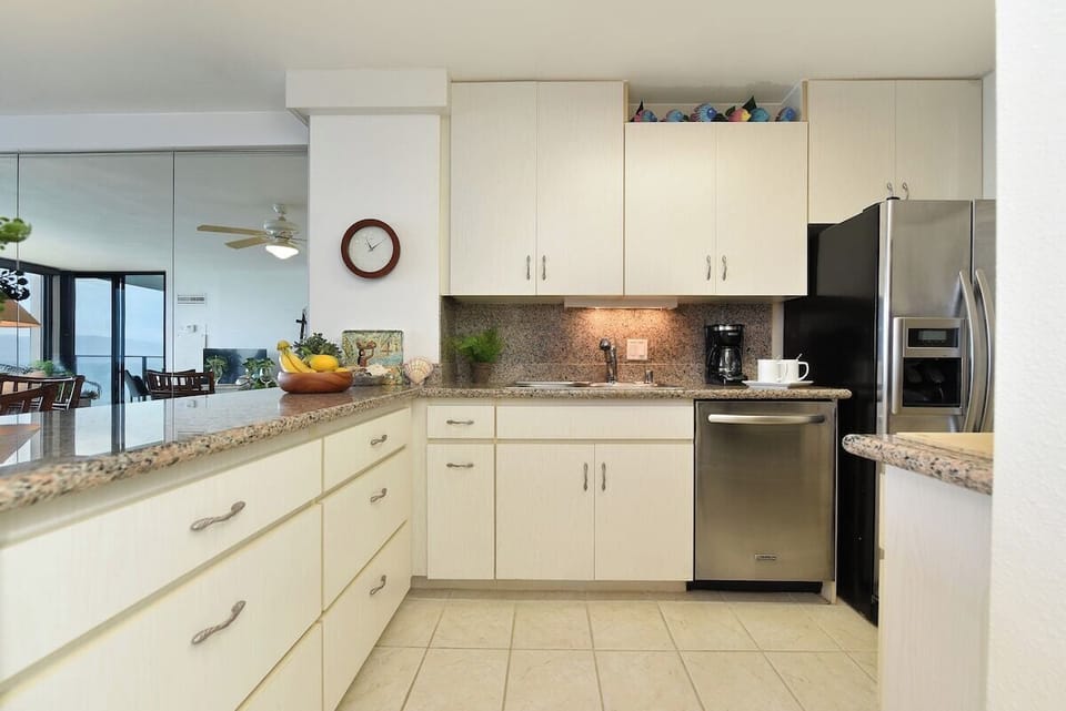 A fully equipped kitchen featuring sleek white cabinetry, stainless steel appliances, and elegant finishes