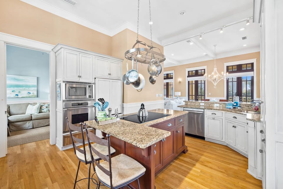 Spacious kitchen, island with cooktop, coffee bar, and outdoor grill on balcony.