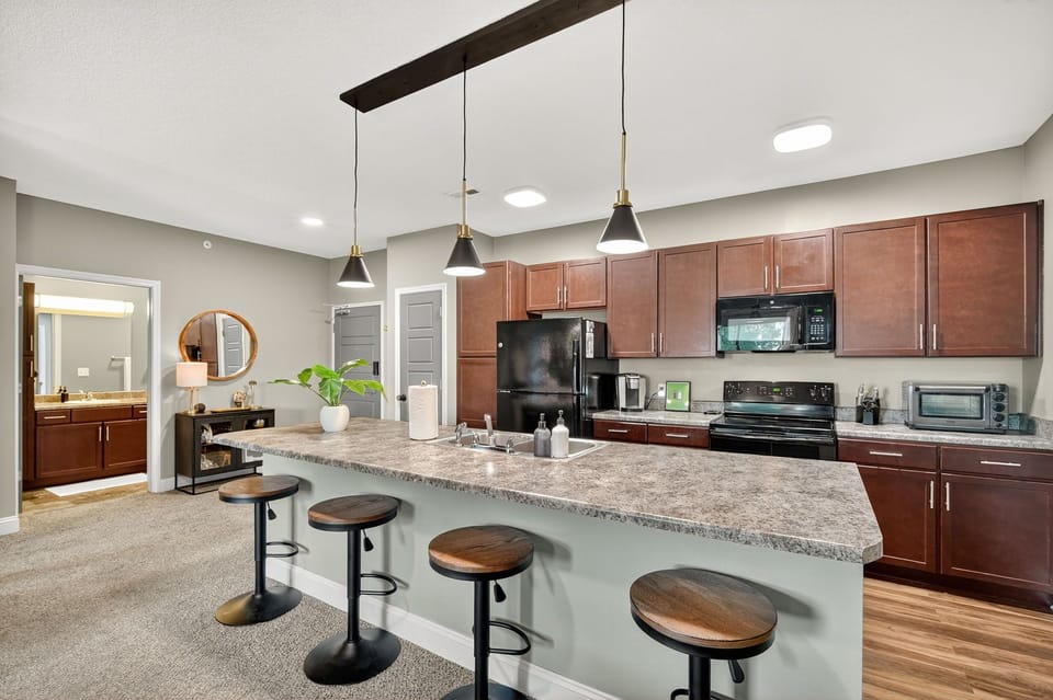 Gather around the huge kitchen island that has seating for everyone accompanied by sleek, black pendant lights for meals, games and more.,