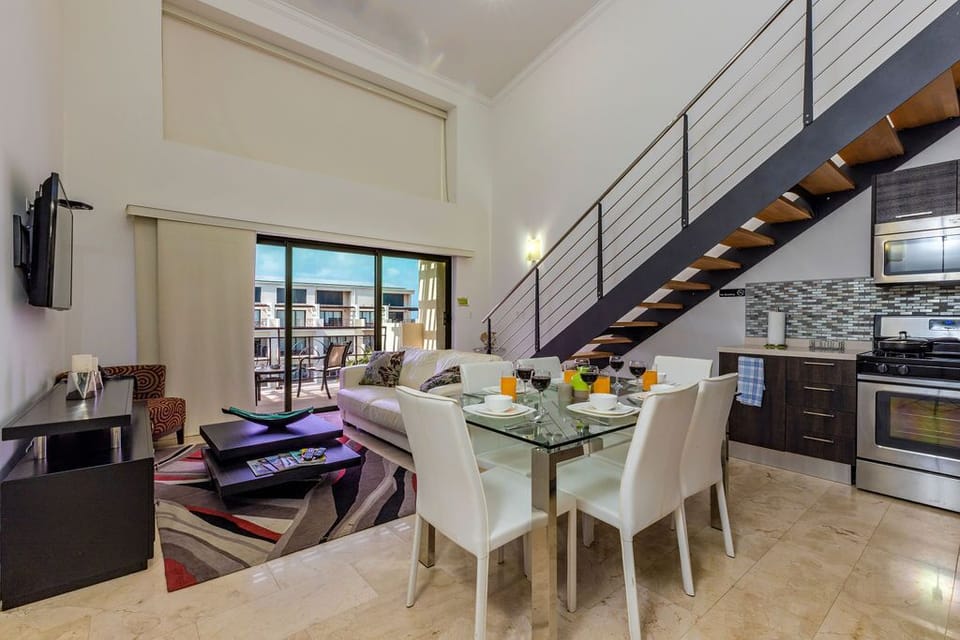 Ample living space with dining table, television, and well-equipped kitchen.