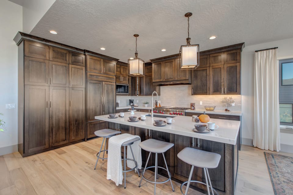 Fully equipped kitchen with stone countertops, stainless steel appliances with stovetop, fridge, and island