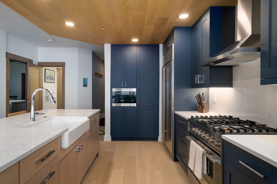 Custom blue cabinetry pops in our kitchen, below the wood paneled ceiling.