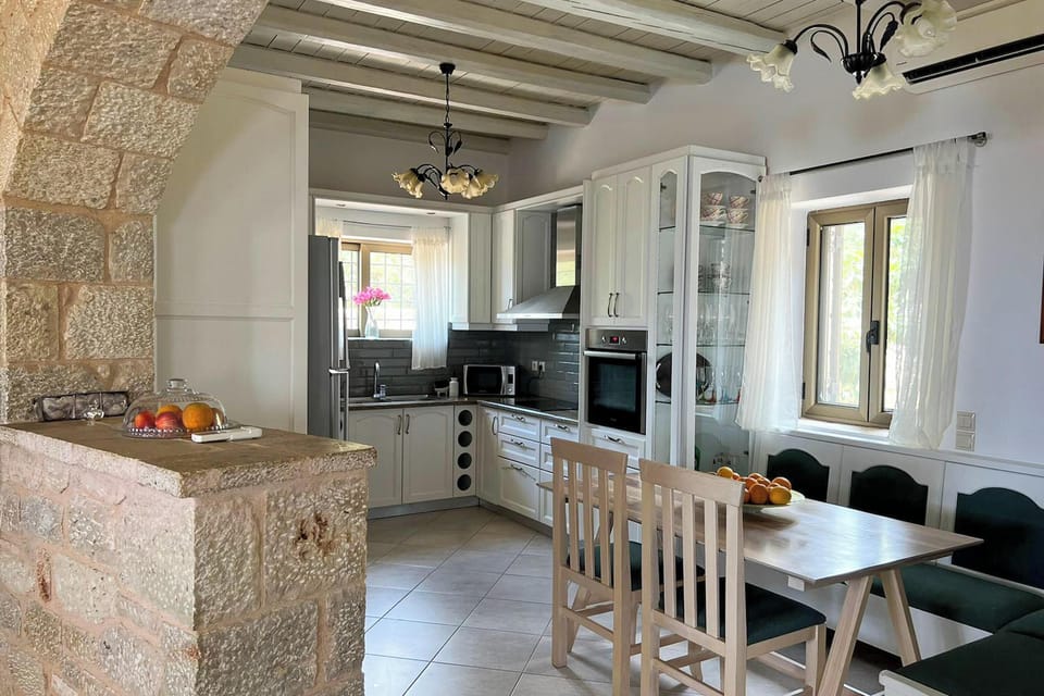 Bright kitchen at the main villa with a dining table, full appliances, and natural light.